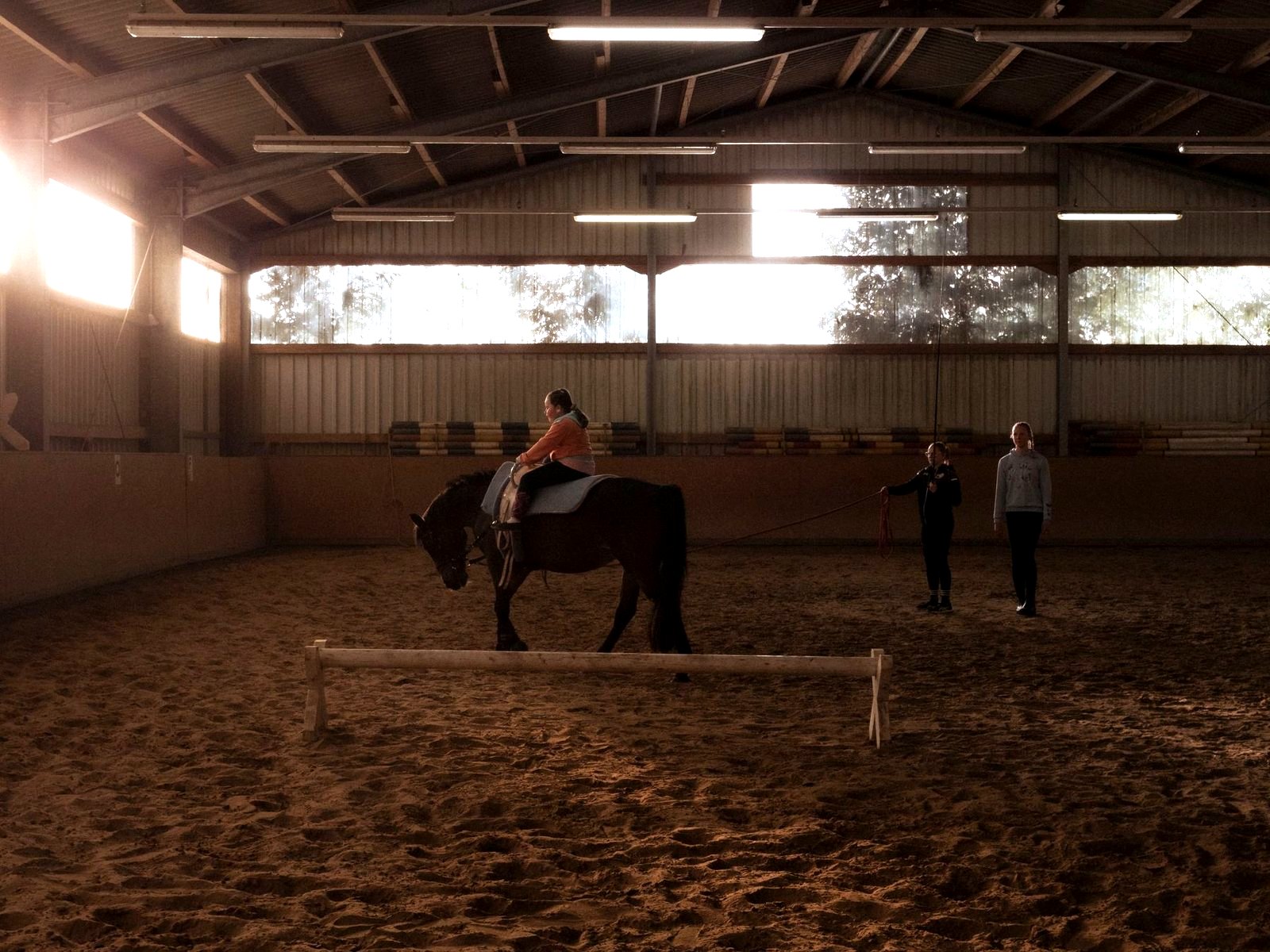 A riding lesson underway in a sunlit indoor arena