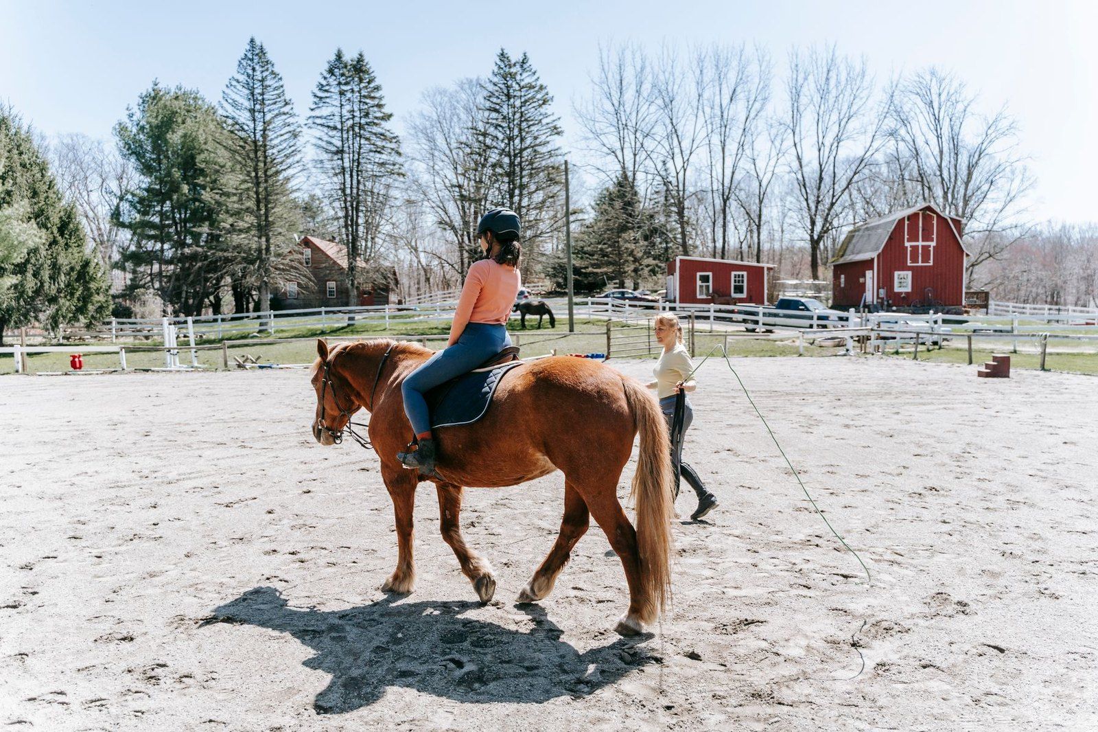 A coach working with a rider in an outdoor sand ring