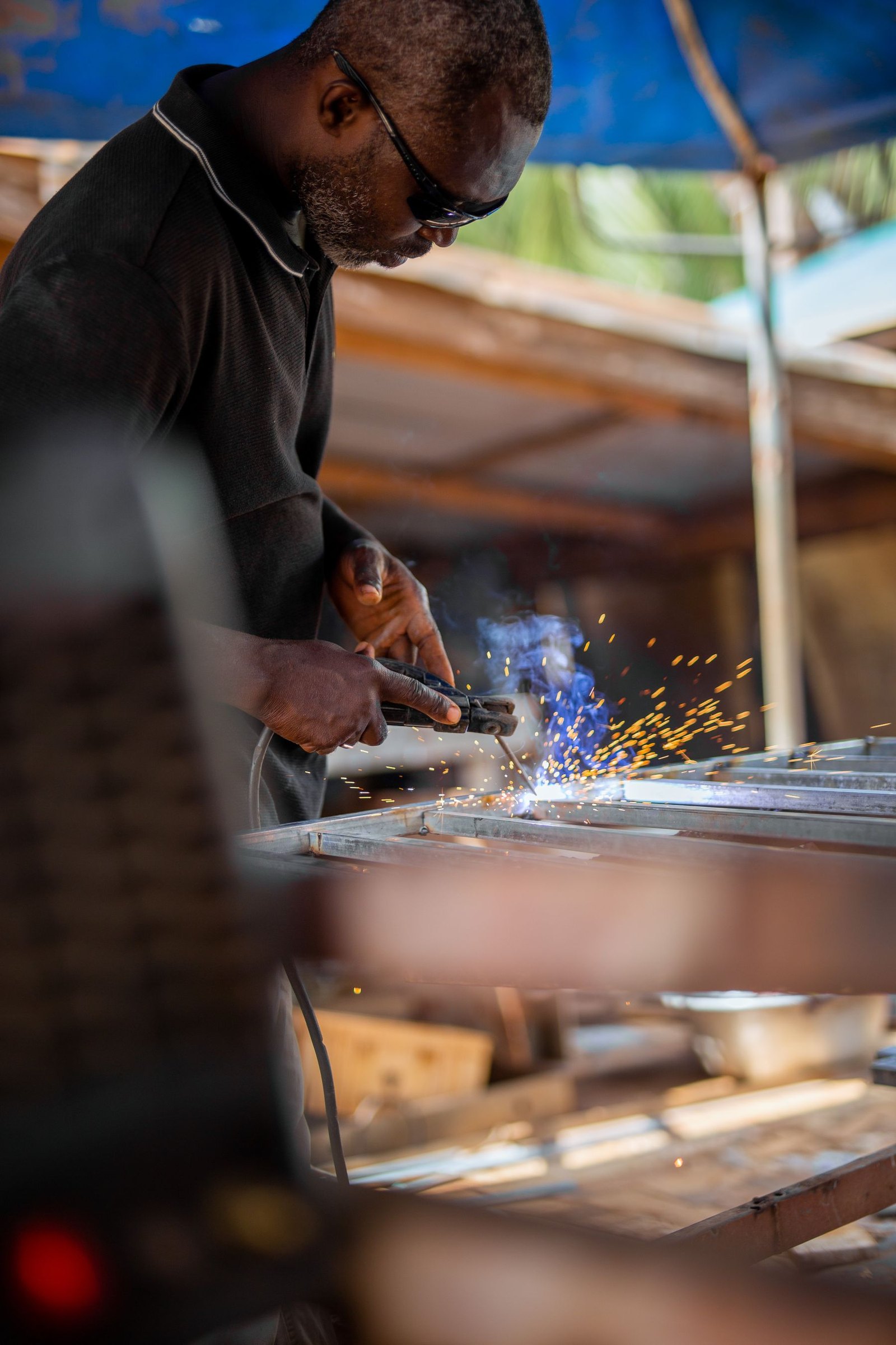 Close view of welding along a steel beam with sparks