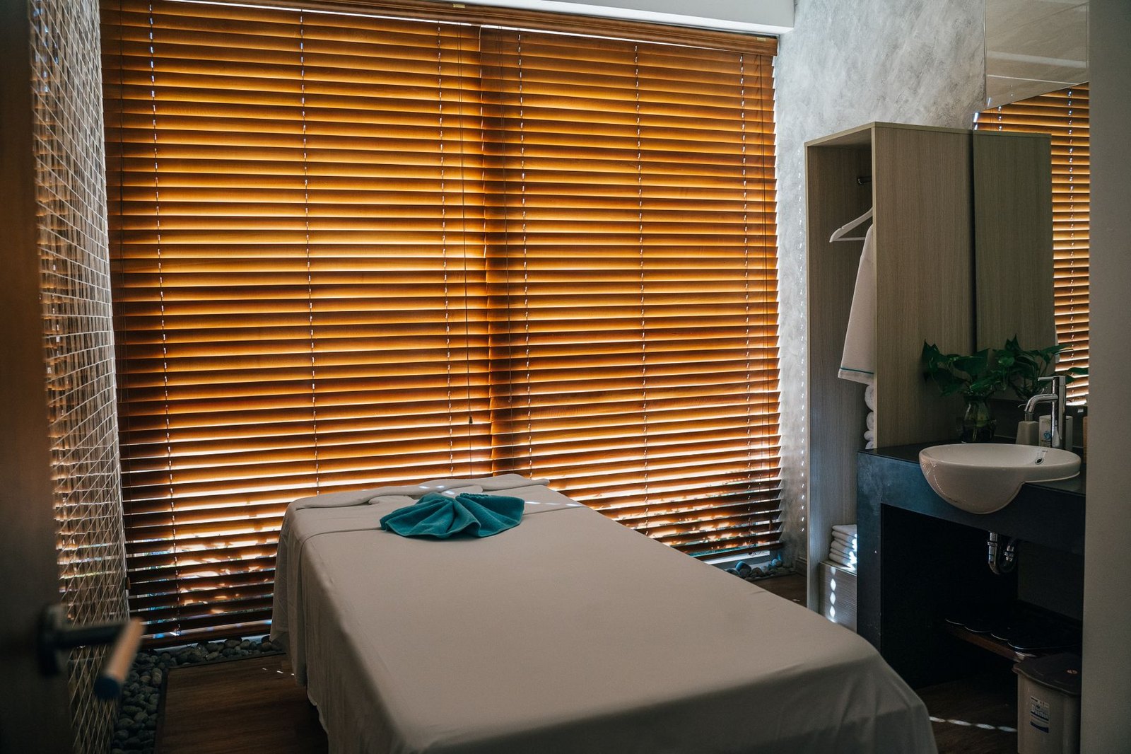 A quiet treatment room with a massage table and warm light through window blinds