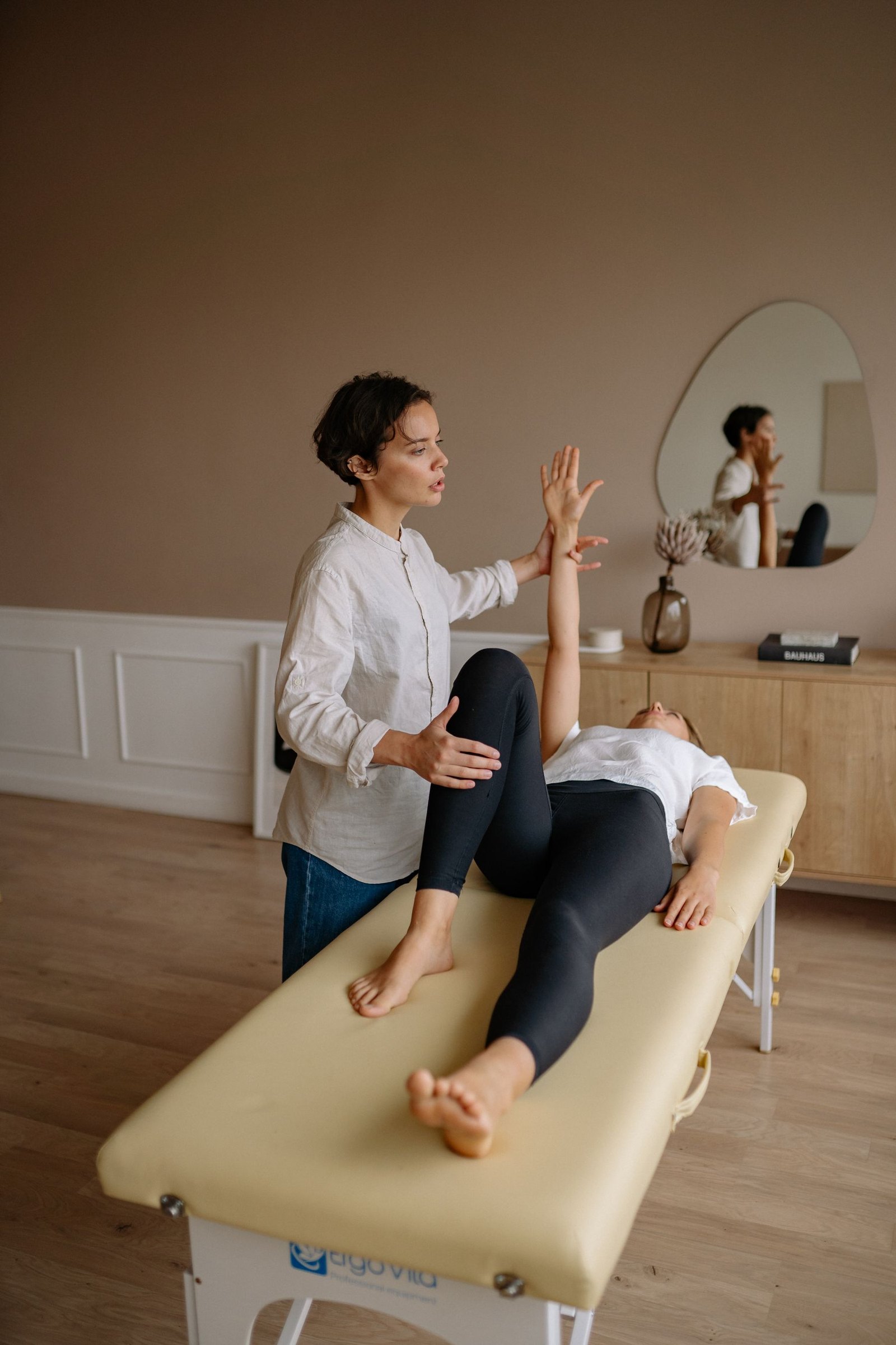 A therapist treating a client on a table in a bright room